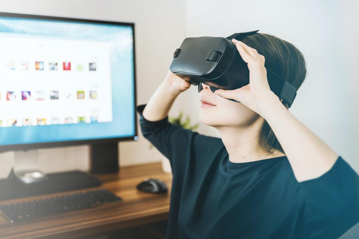 A person wearing a VR headset at a desk beside a computer