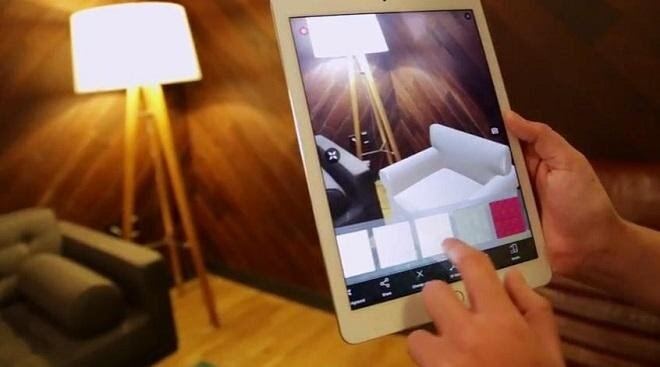 Hands holding a tablet that places furniture in a room with augmented reality